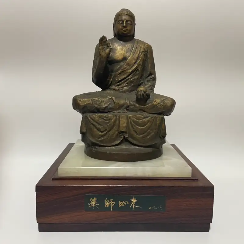 北村西望作のブロンズ仏像「薬師如来」坐像の全身。左手に薬壺を持ち、右手を挙げた姿